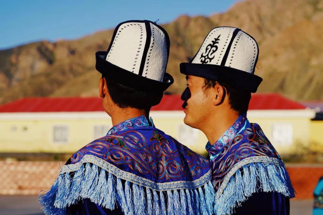 他们身着柯尔克孜族的特色服饰,男士头戴白色毡帽,女士服饰色彩明艳