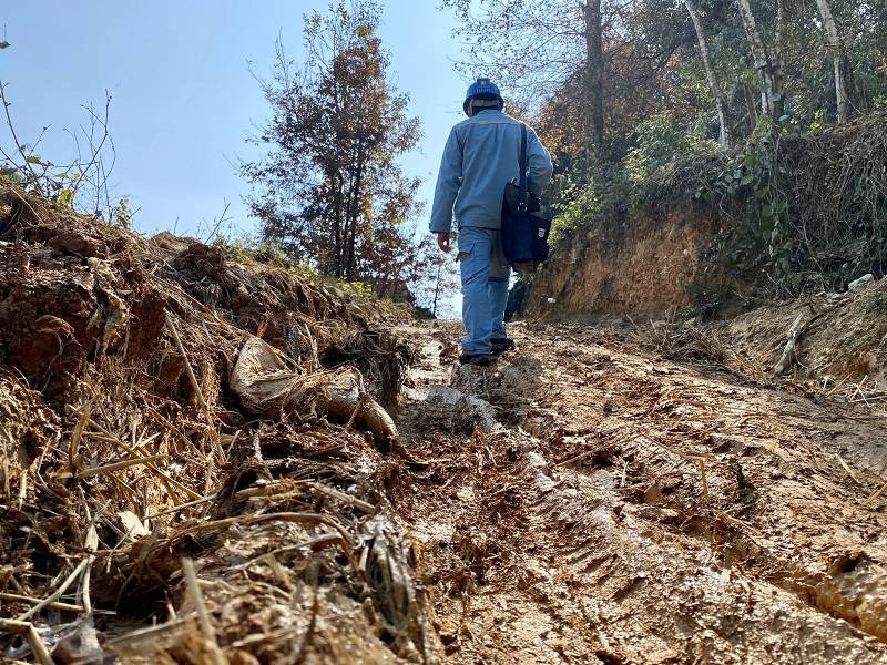 抢修人员在泥泞的道路上艰难前行.