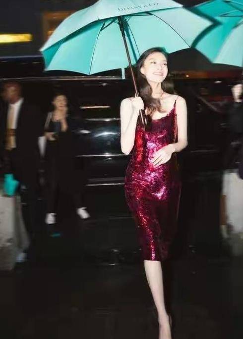 2018年,倪妮在国外出席活动时,身穿酒红色亮片裙,撑伞漫步的氛围照片