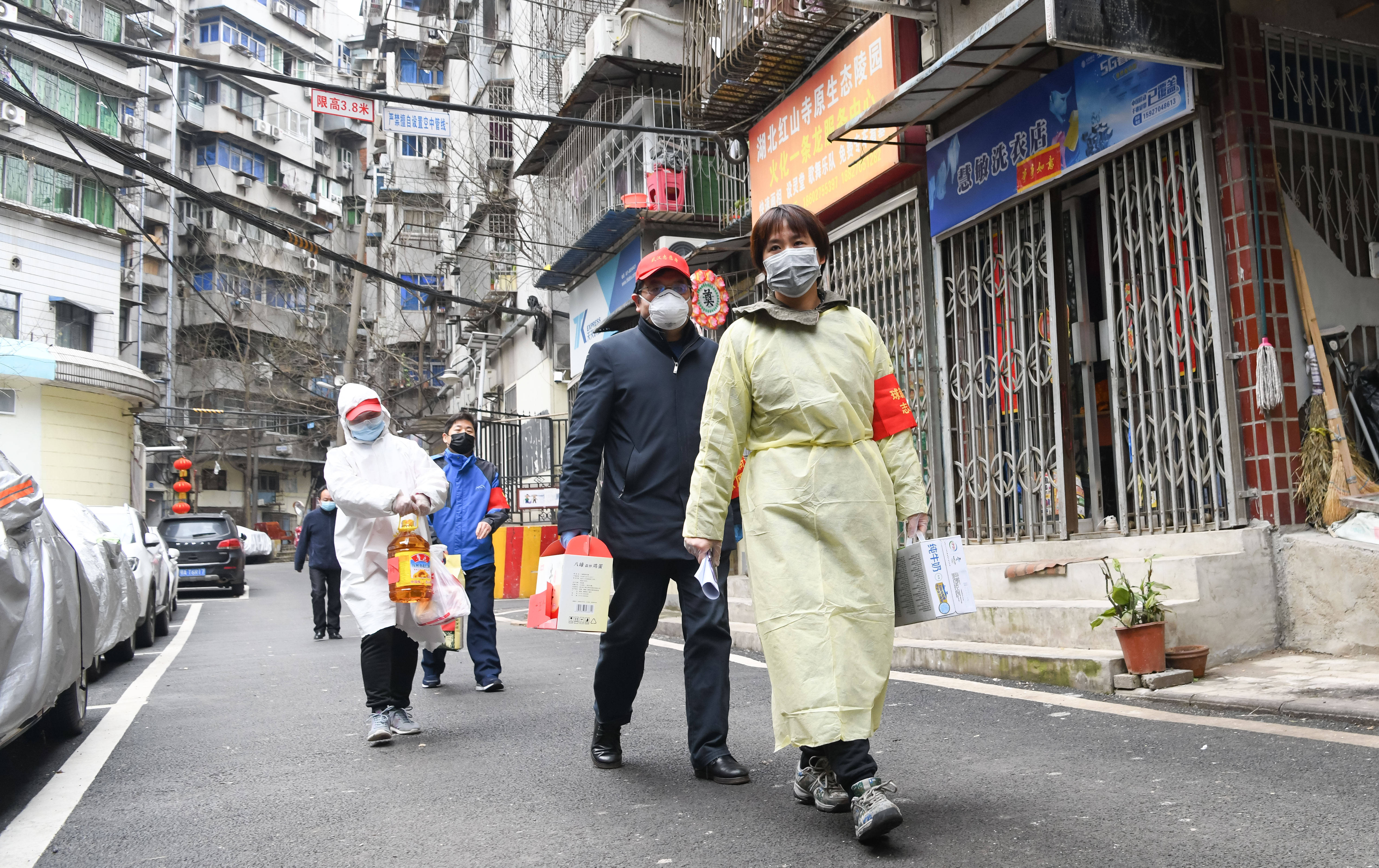 3月2日,武汉市江岸区球新社区干部郑捷(右一)和志愿者为社区里的低保
