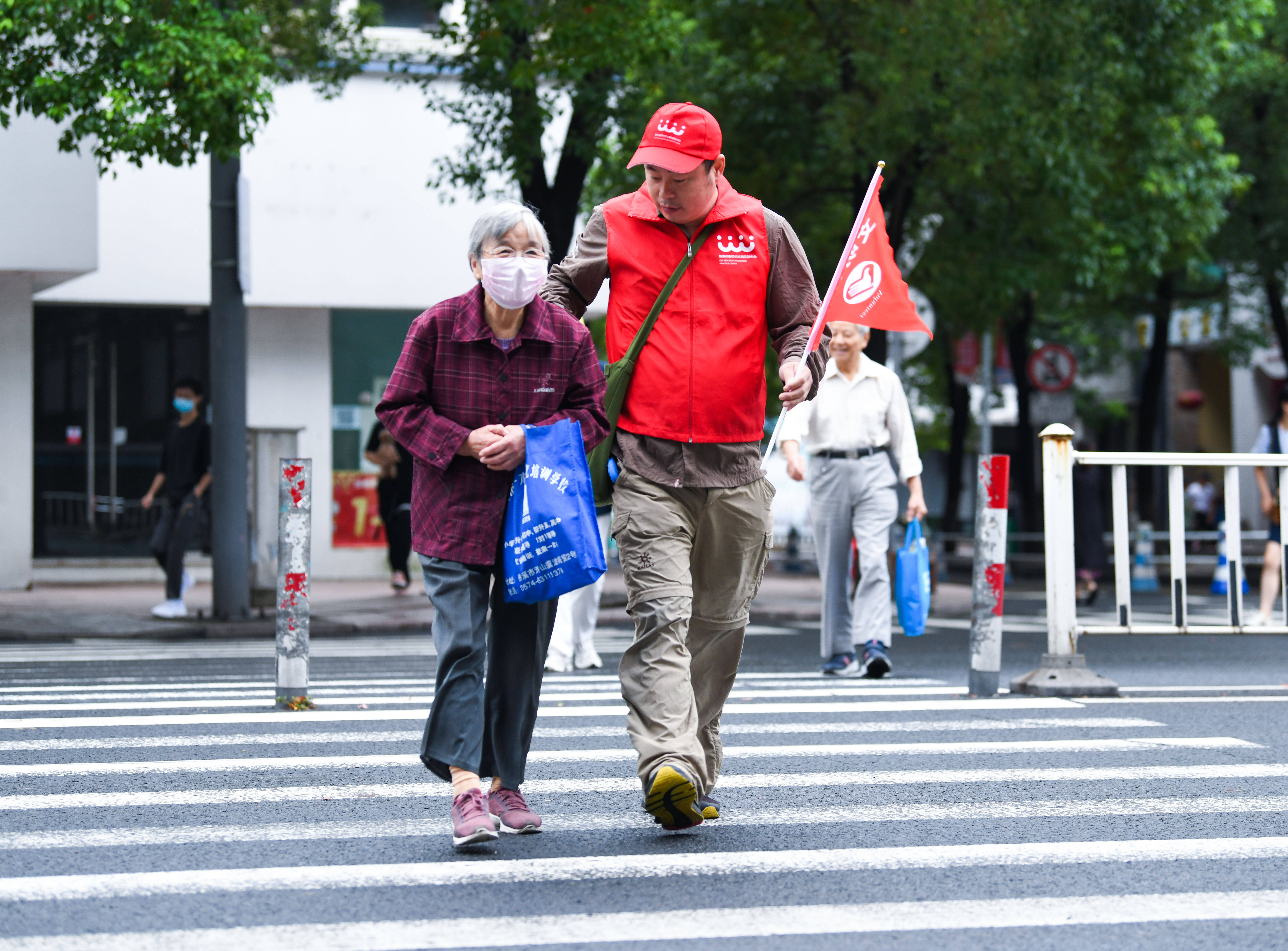 市钱海军志愿服务中心的志愿者在慈溪市三北大街路口帮助老人过马路