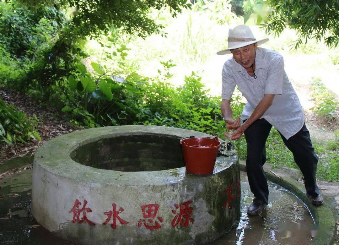 只见圆圆的井墙上写着"饮水思源"四个字,村民正在井边