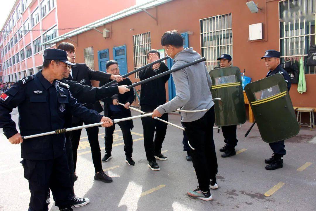 扮演的"暴徒"手持菜刀强行翻越校门,闯入校园,学校立即组织教师到位