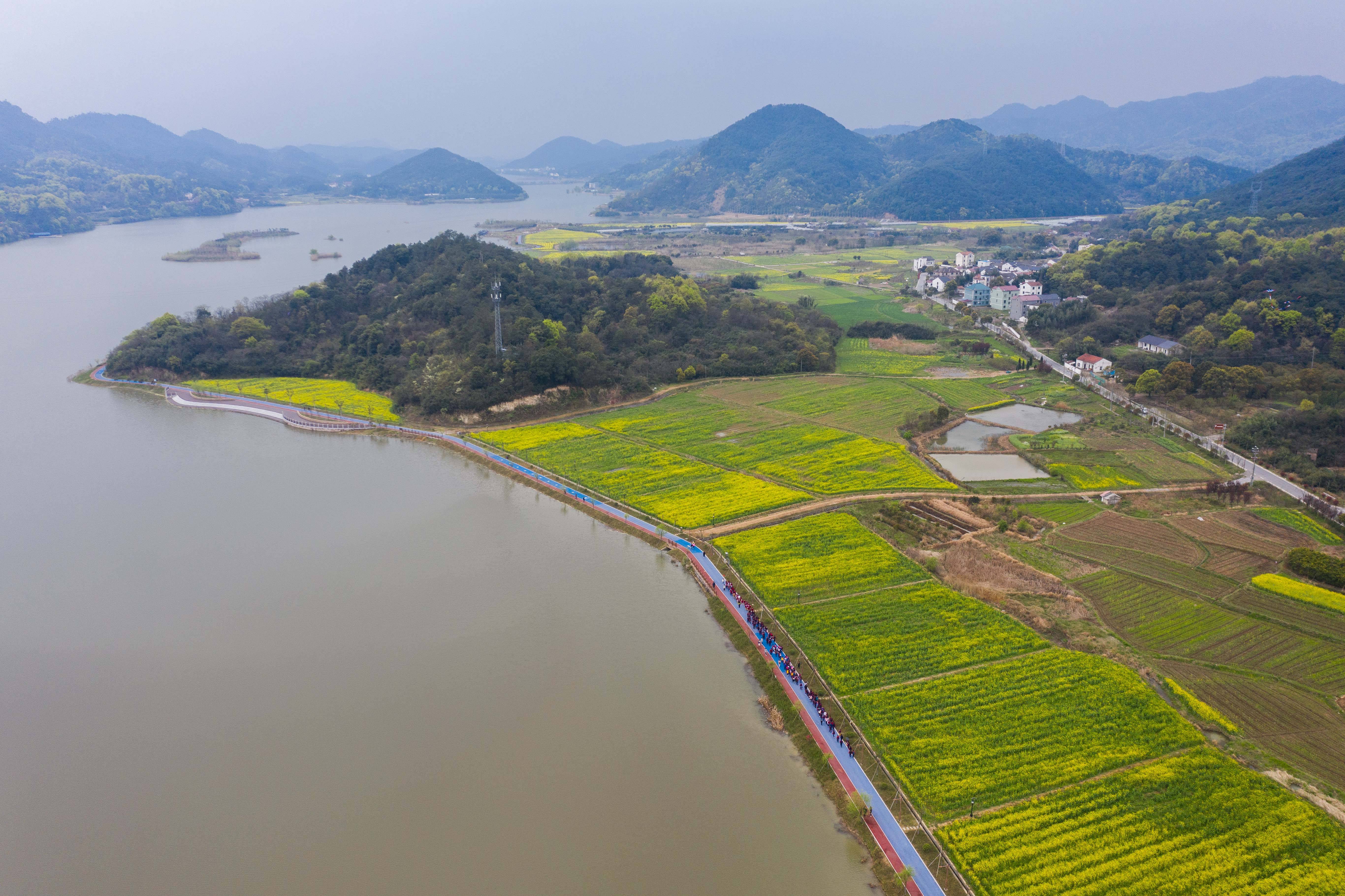 3月24日,春游的师生在诸暨市同山镇布谷湖的环湖路上观赏春色(无人机