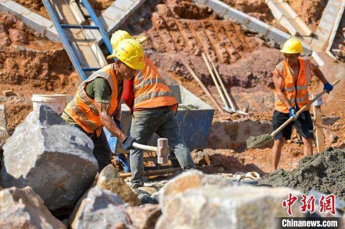 图为在国道g360文临公路文昌段项目施工现场,工人在烈日下施工.