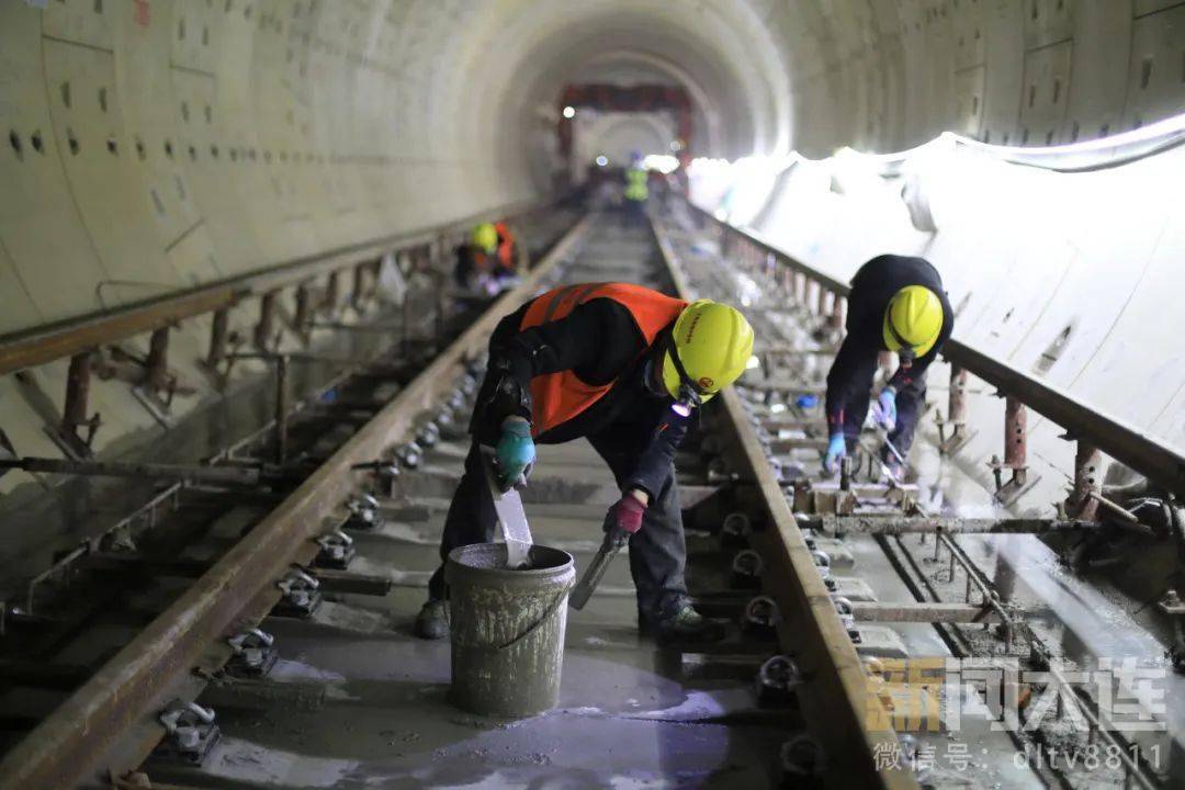 只见一台铺轨小吊车正在将地面拼装好的"轨排"从轨道运输车上吊起