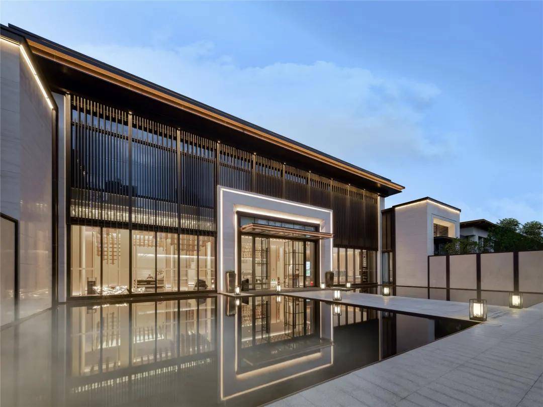 水景两侧由米白色纹理仿石瓷砖干挂而成的景墙,售楼部建筑外观的景致