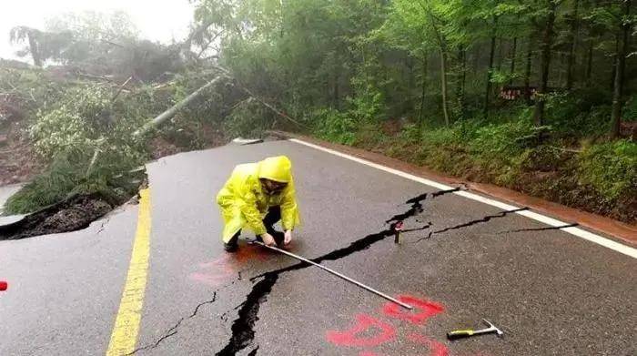 地质人员正在测量受损道路,划定标点观察裂缝变化情况.