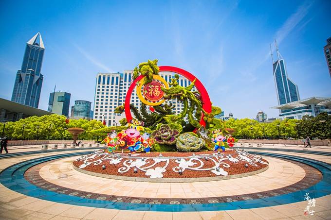 在人民广场上摆设了大型花坛,各种植物草木构造出喜庆图案,应和着上海