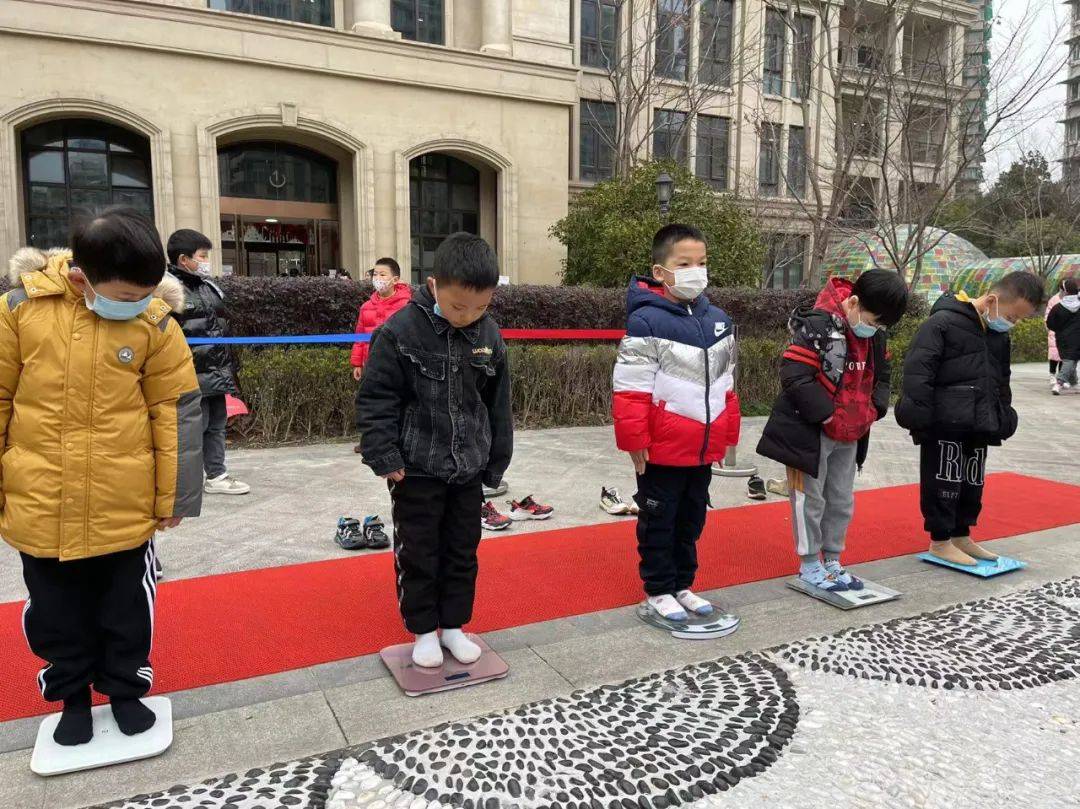 市新华实验小学操场上,五台电子秤一字排开,各班学生排着队,脱掉鞋