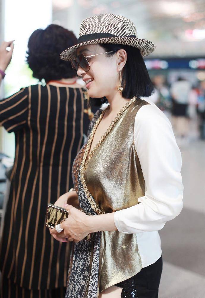 原创49岁钟丽缇走机场穿深v短裙高调秀美腿比小12岁老公还要年轻