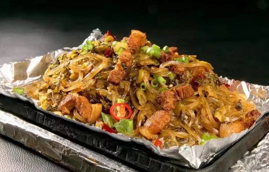 用铲子翻炒,再将酸菜堆到一旁,铁板中央加豆油,大火加热,下入五花肉