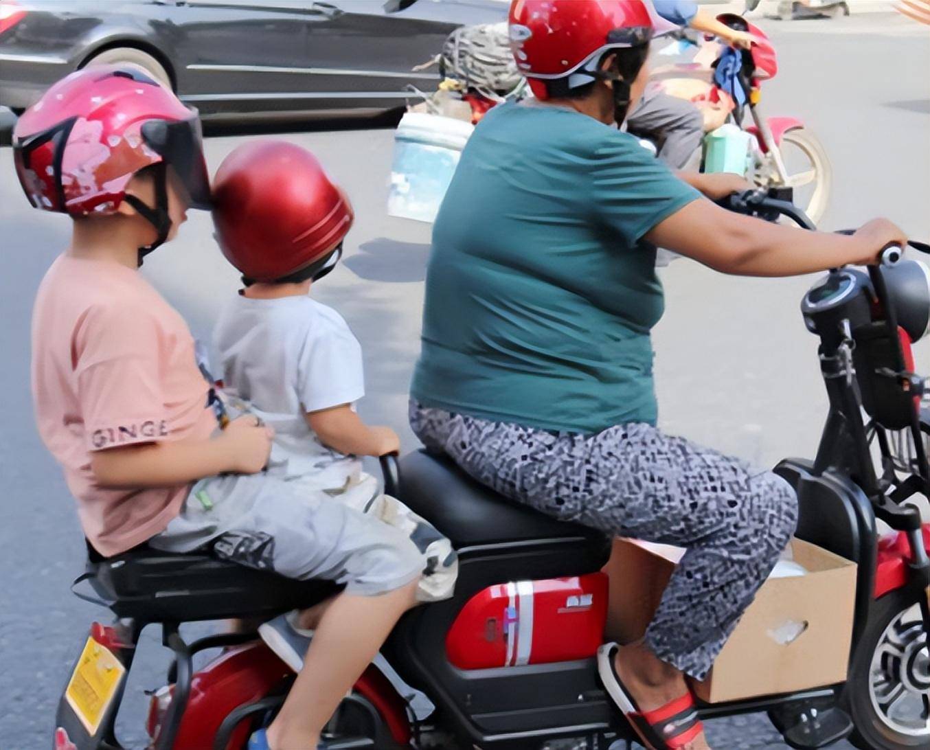 二胎母亲骑车送俩娃上学,途中被交警阻拦,家长无奈:要扔一个?