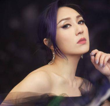 舞台上的杨千嬅身穿带有花朵的深紫色抹胸长裙,发型和指甲的颜色也都