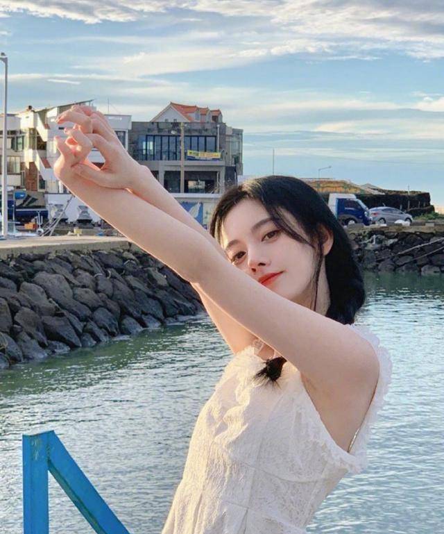 照片中的鞠婧祎站在蓝天白云大自然做风景,又身着一袭白色吊带裙站在