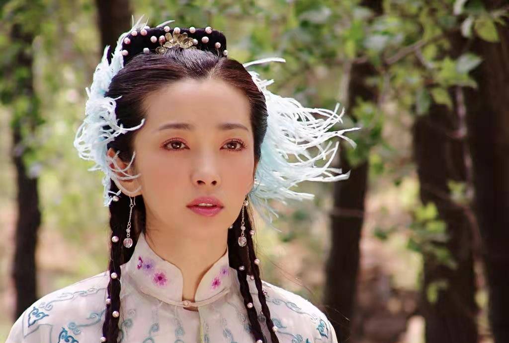 额头一条朴实无华的链子,发髻下方各插一支孔雀翎,很有江南女子的娇俏