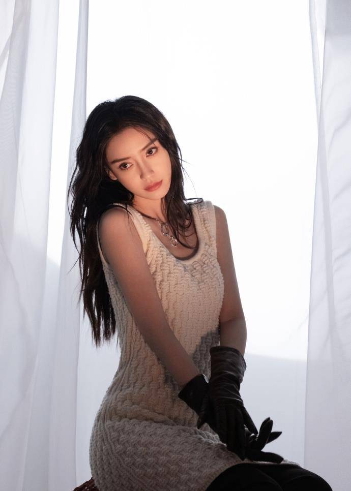 图中,angelababy身穿白色针织背心裙,搭配黑色打底裤,手上戴着黑色