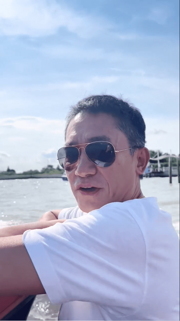 视频中,梁朝伟戴着墨镜,穿着简单的白色t恤,两手抱臂呈现