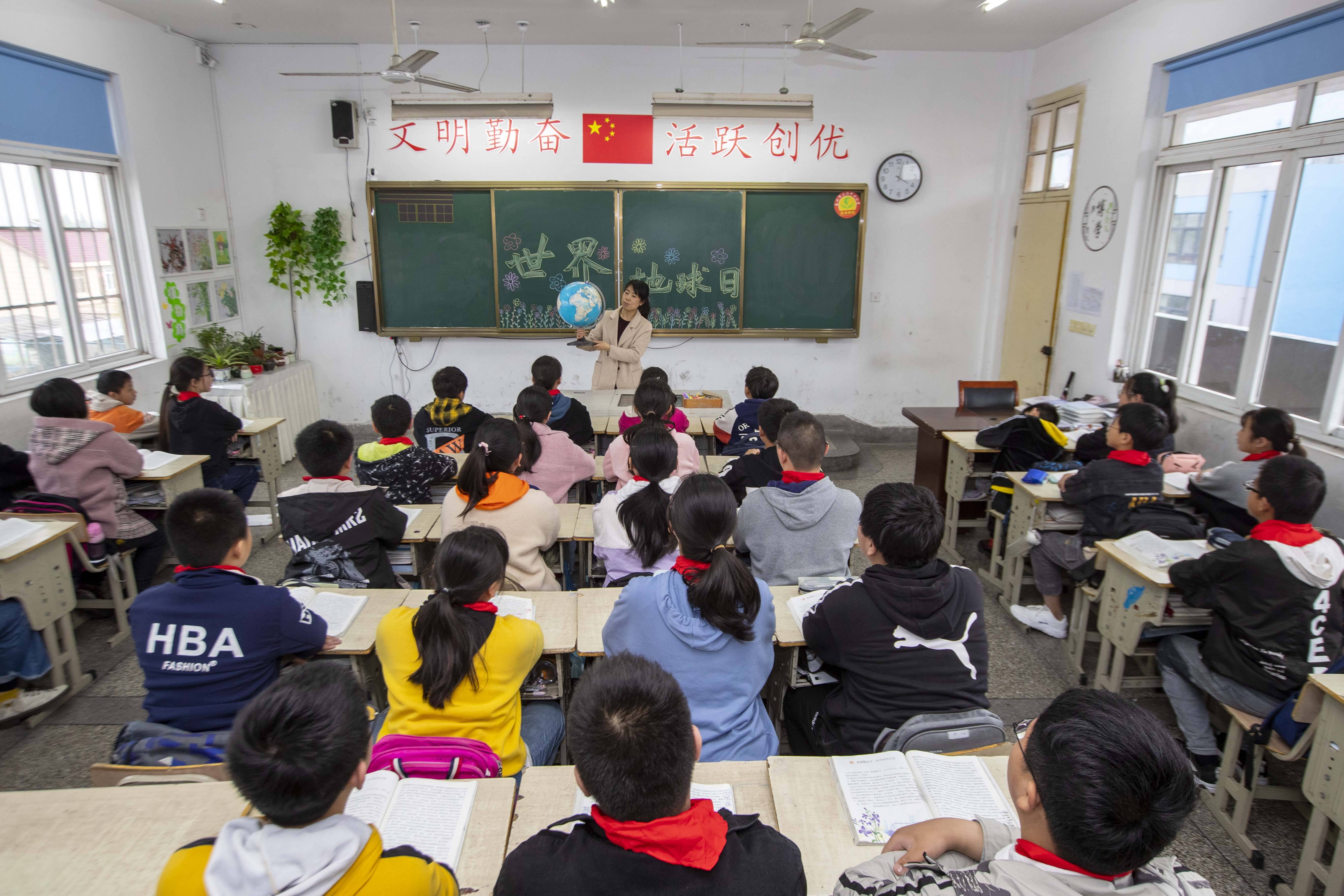 2021年4月22日,在江苏泰州市大冯中心小学,小学教师为学生讲解地球