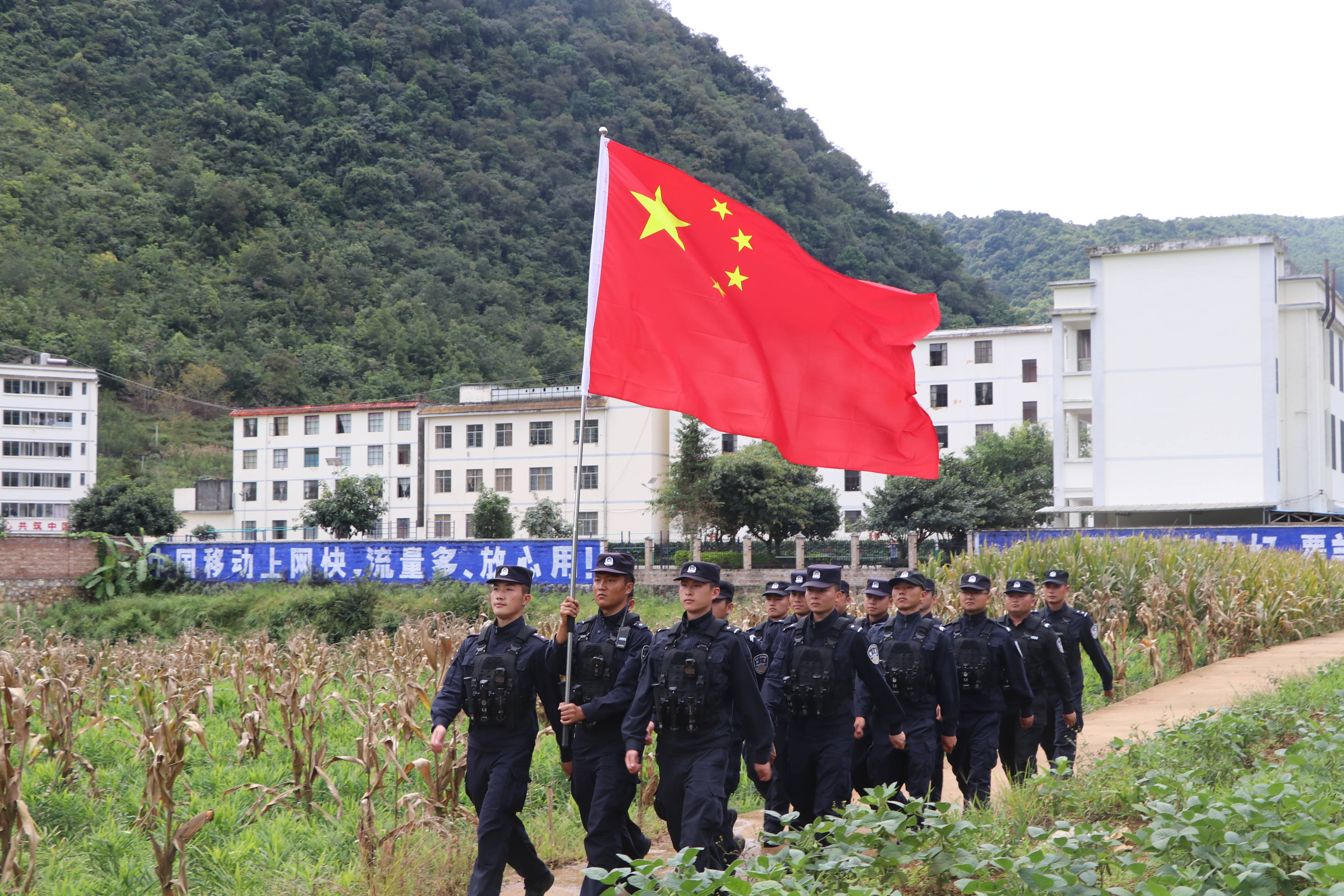 云南文山边境管理支队坡脚边境检查站民(辅)警扛着国旗在边境线上巡逻