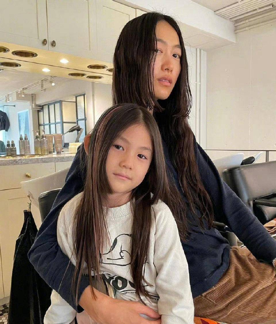 两人的女儿穿着黑色的卫衣,扎着丸子头,和妈妈秦舒培