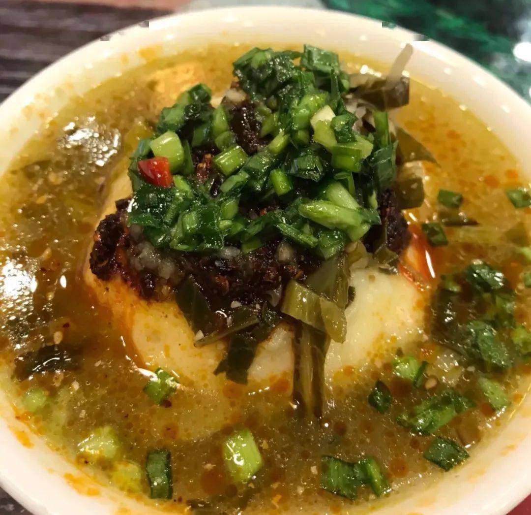 舀出洋芋泥,搁在 浆水里,再 淋一勺油泼辣子和翻炒后的 韭菜.