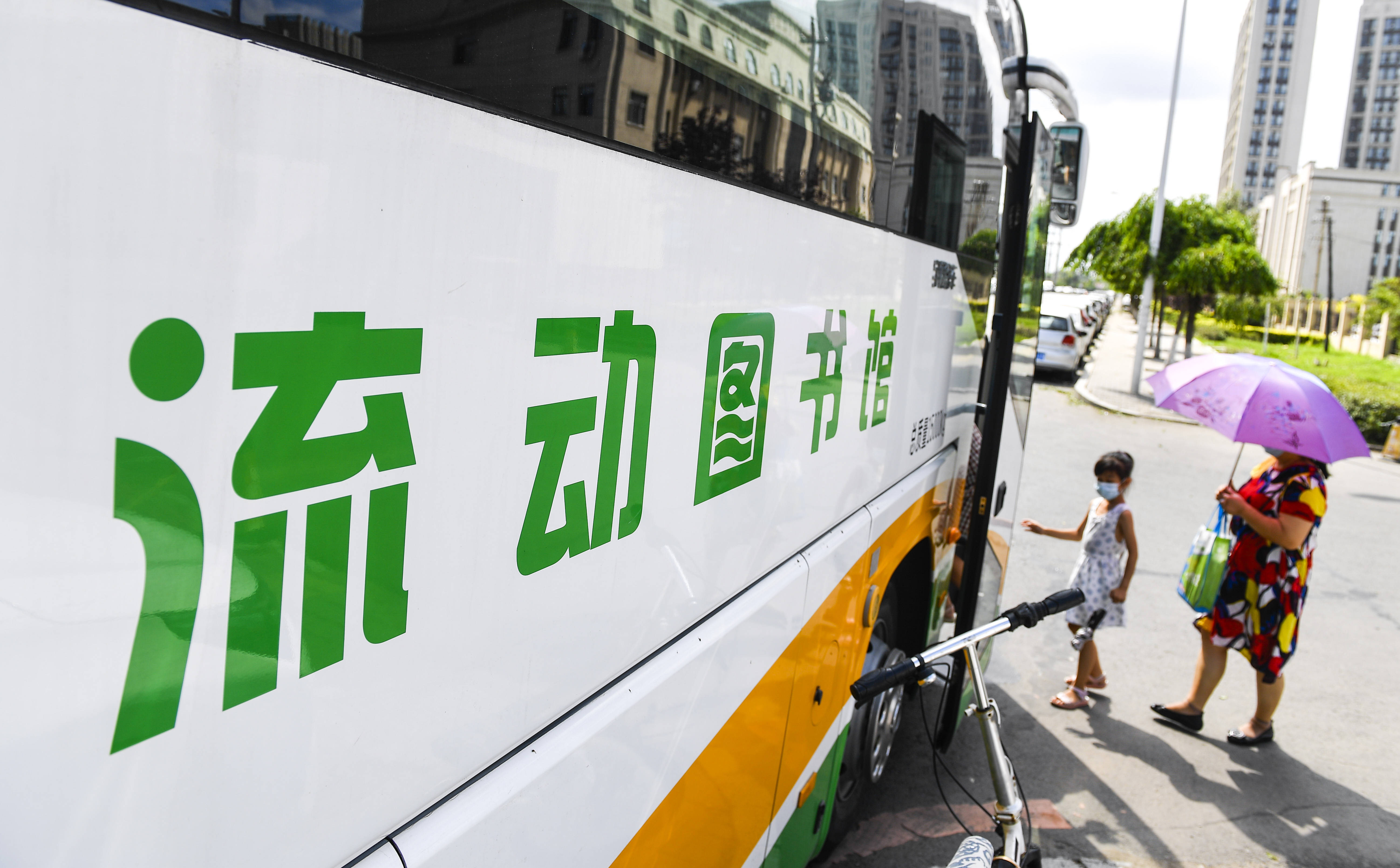 8月5日,在长春市一处社区服务点,市民进入"流动图书馆"借阅图书.