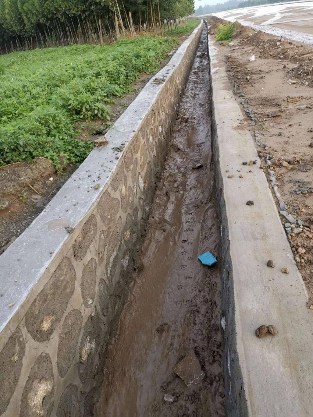 道路两侧用石头垒砌的边沟对道路边缘进行修整道路施工有条不紊运料车