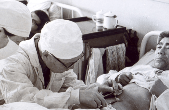 傅培彬在为病人换药他要求实习医生:"问病史时,最好搬个凳子坐在病人