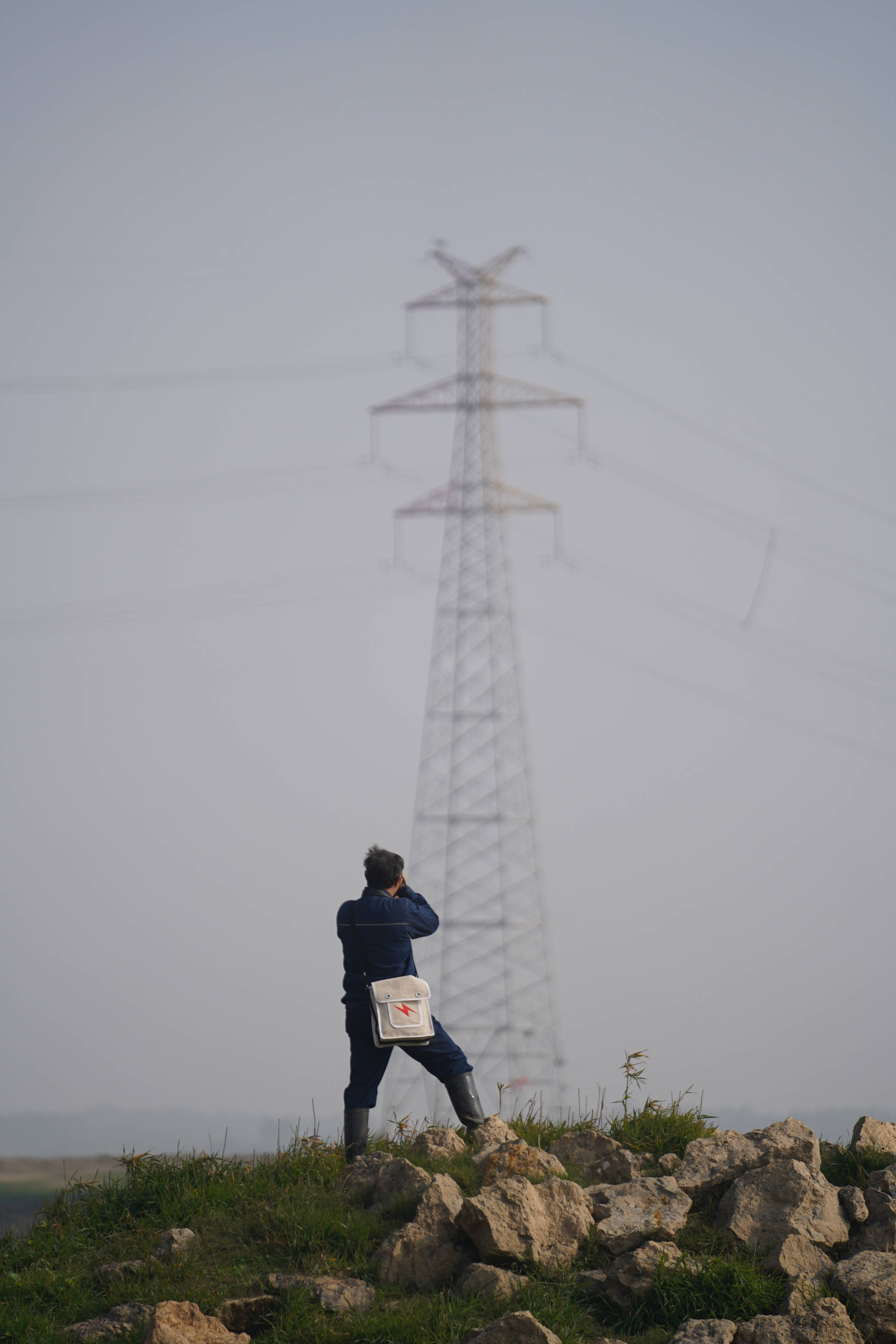 電力工人在遠處觀察鐵塔上的鳥巢(12月12日攝).