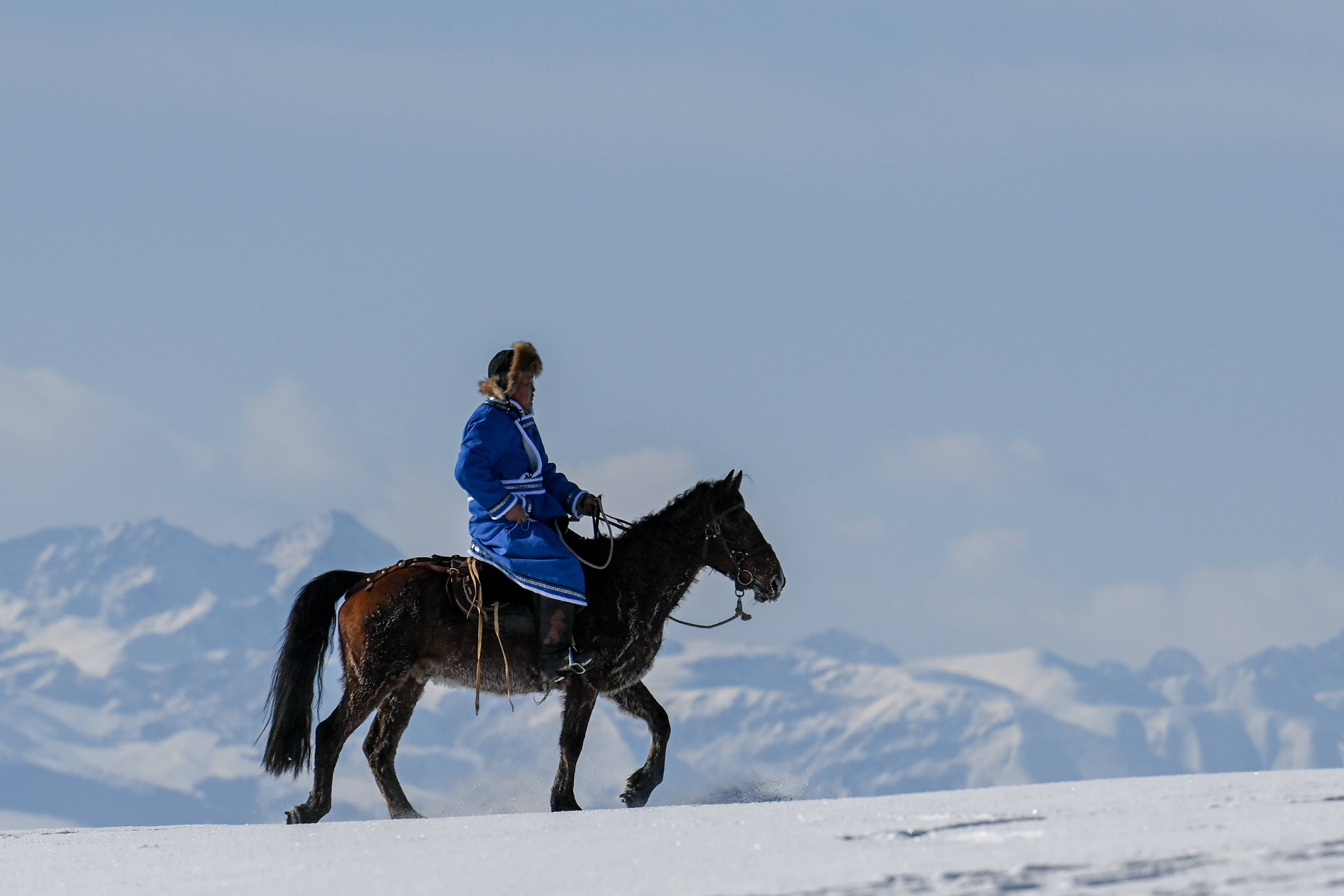 在新疆伊犁哈萨克自治州昭苏县,一位牧民骑马走在茫茫雪原中(2020年12