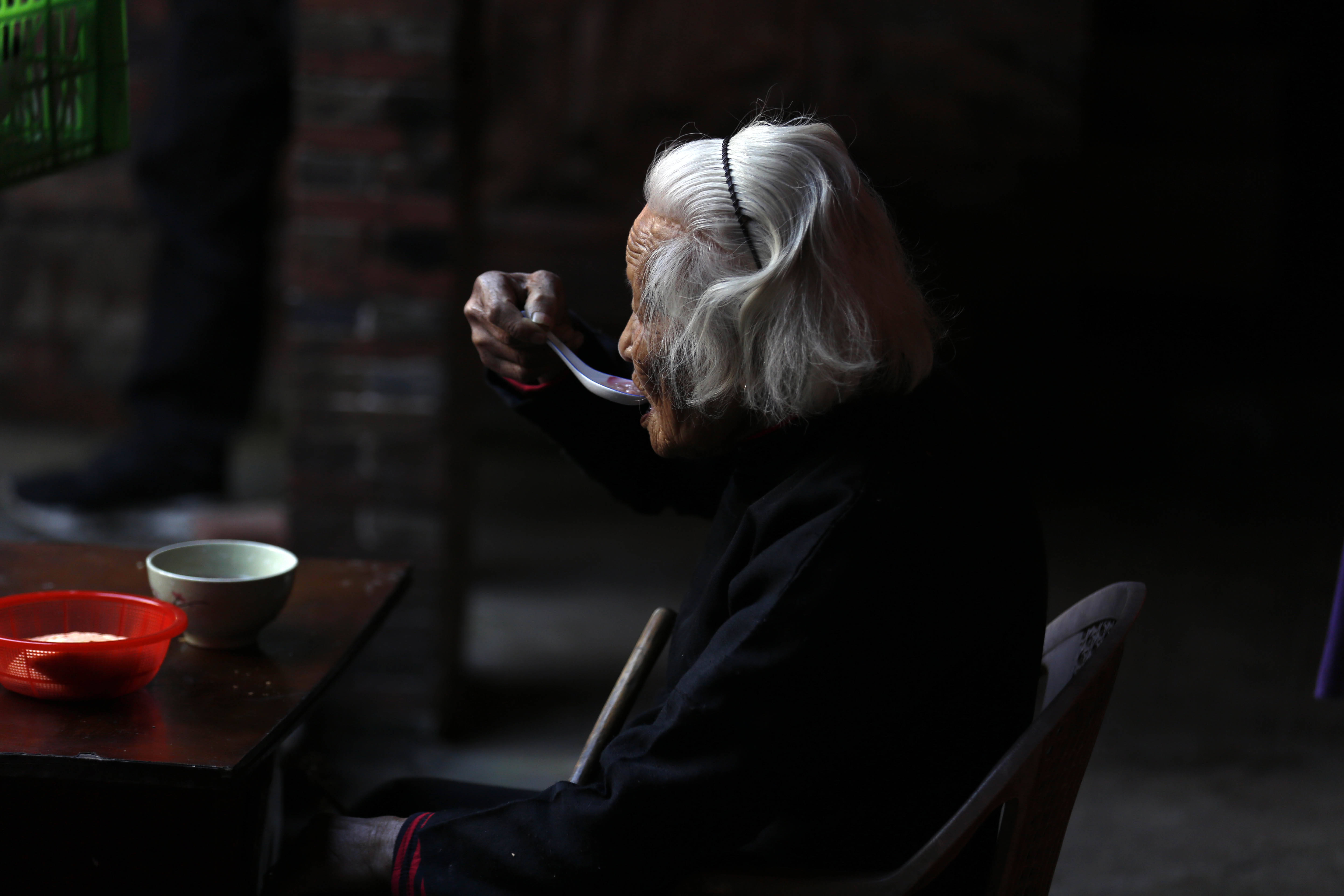 饭后,老人不紧不慢收拾桌面,身后的洗脸架伴随着老寿星近90多年.