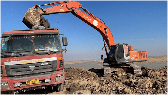 作业,湿度极大的淤泥在冬日里冒着白气被挖起装入川流不息的运输车辆