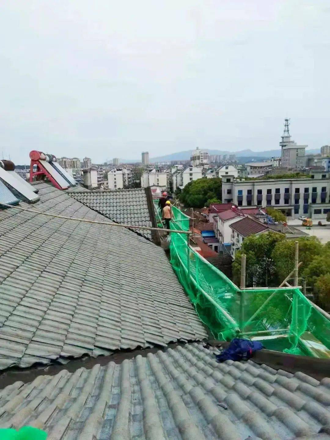 走近夕阳红小区,多幢居民楼楼顶在搭设防护栏,工人们正在清理屋面及