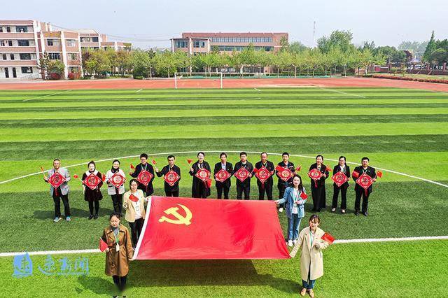 宿迁市第一实验小学全体党员穿戴整齐,在优美的校园用"与党旗合影"的
