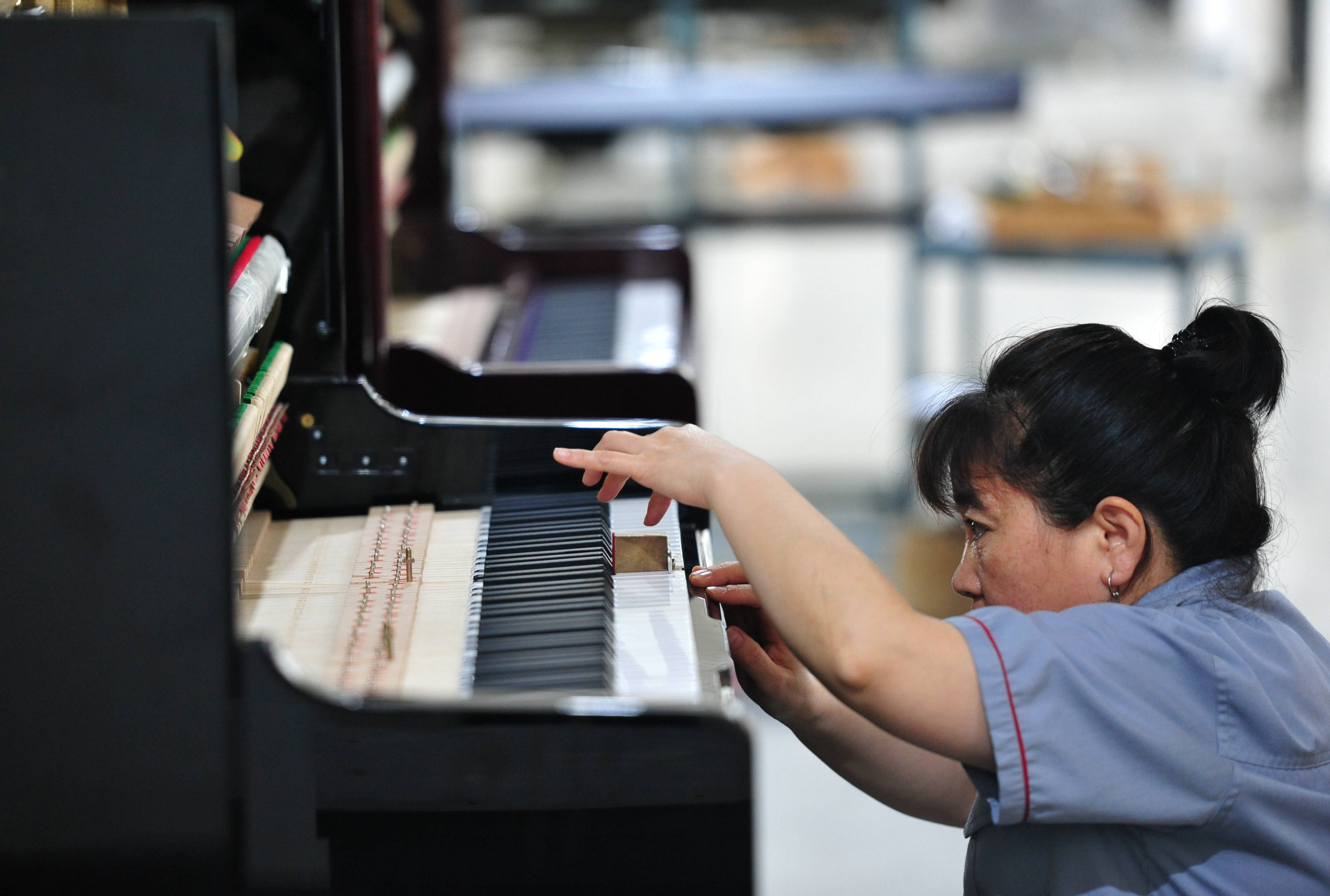 7月22日,河北省肃宁县一家乐器生产企业的工人在钢琴生产车间工作.