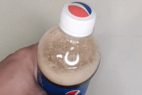 方法非常简单,只需要用手指沿着瓶身中间部位弹几下,像这样将可乐瓶弹