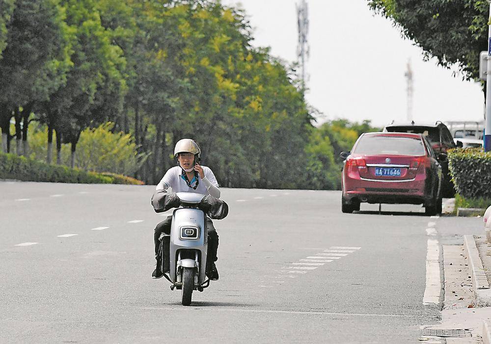 合肥市望江西路,一名市民駕駛電動自行車在機動車道上逆行,邊騎行邊接