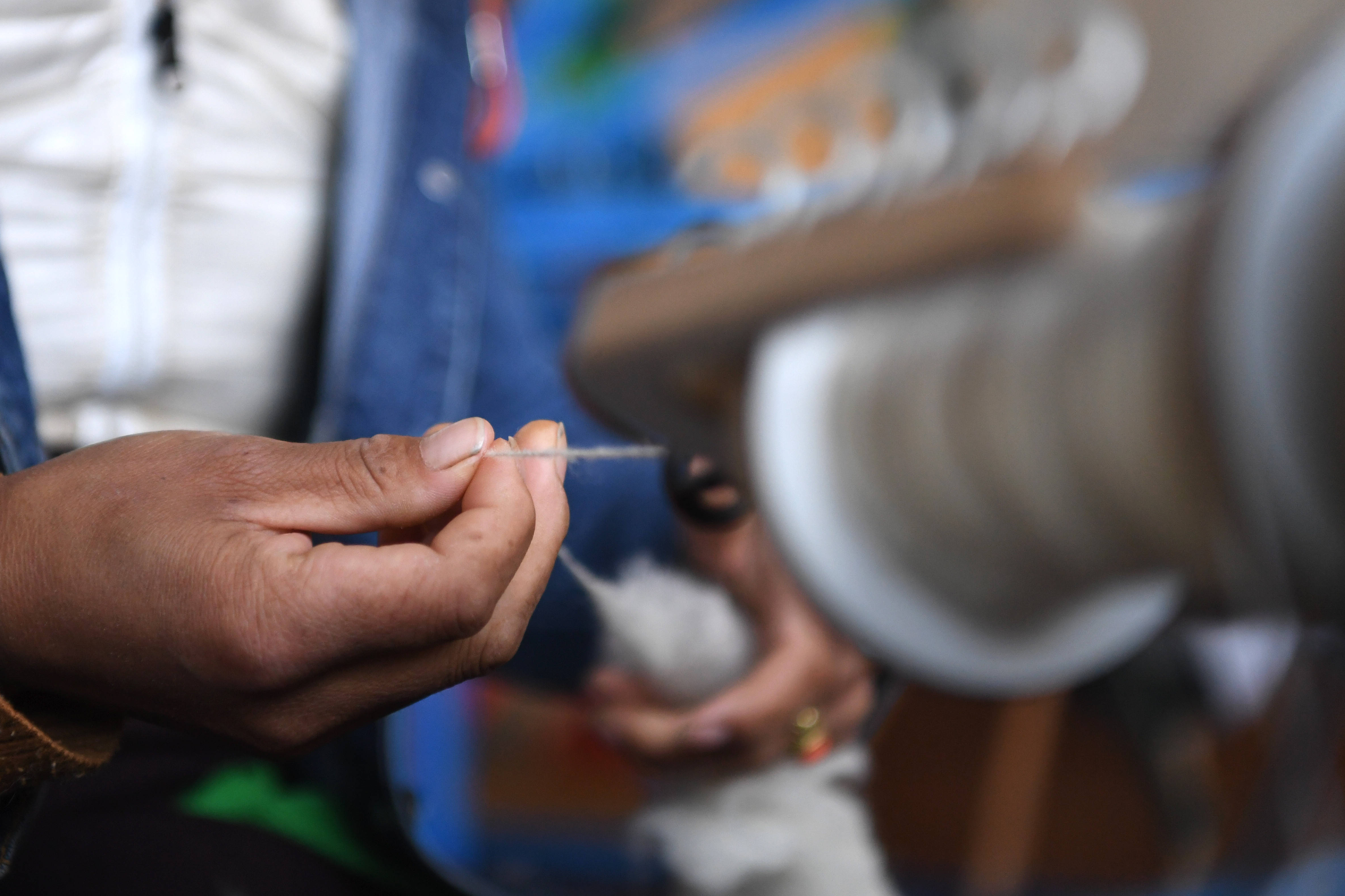 加科村村民拉周玛在藏族手工艺品车间里手工捻线(9月9日摄).