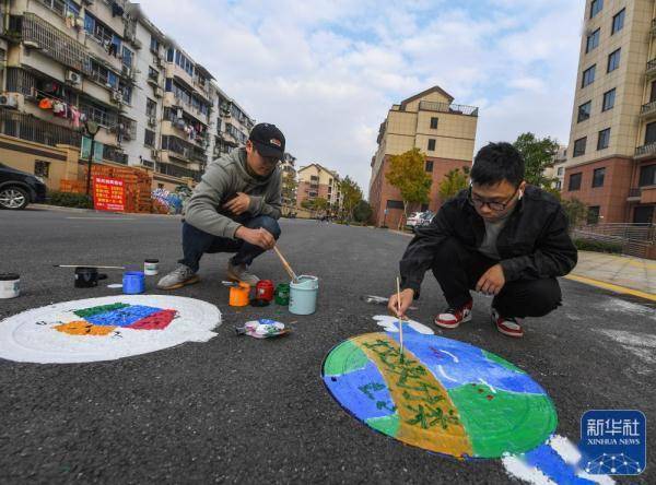 11月18日,大學生志願者在龍泉街道祥和社區的井蓋上手繪圖畫.