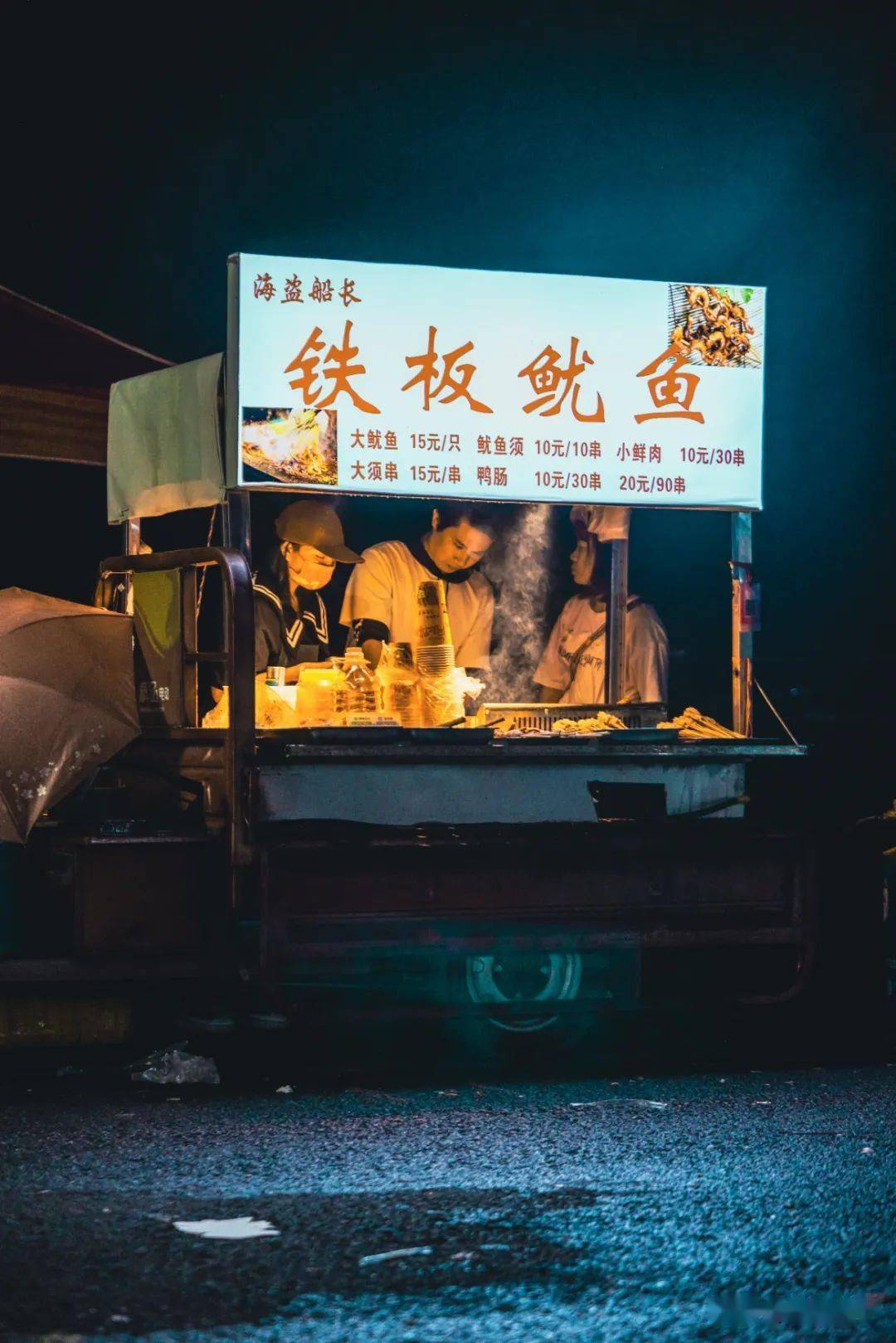 顺着夜晚的人流走到铁板鱿鱼的摊前,我们终于如愿以偿抢到了最后一个