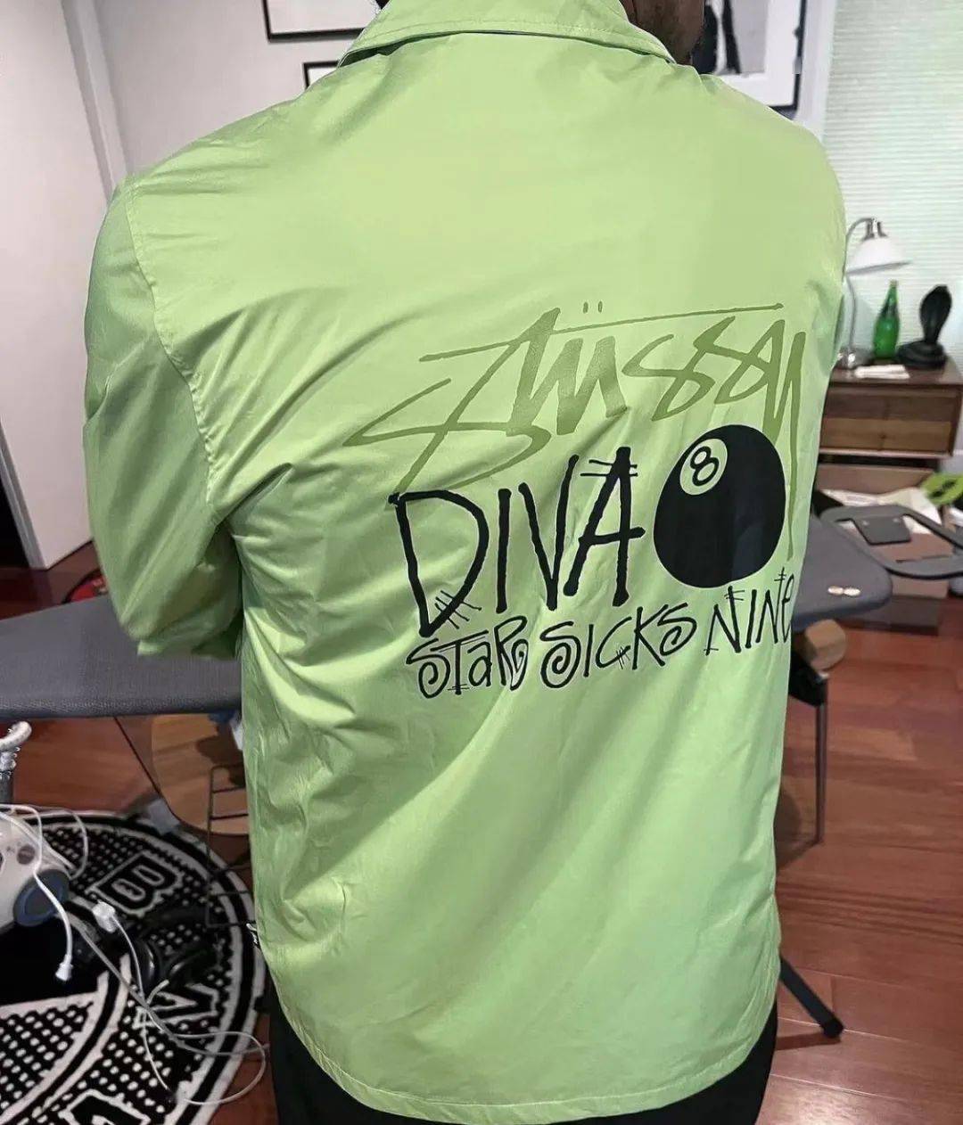 一款荧光绿配色的教练夹克背后是经典黑八台球和stussy logo的设计