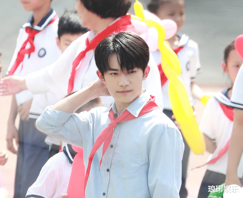 想必这一次录制节目应该是在小学里面,带着红领巾的千玺被一大堆可爱