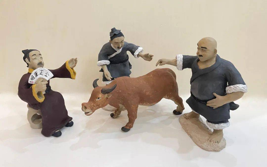阳东正雅学校美术教师李健德一边给泥塑作品《于太守断牛》上色,一边