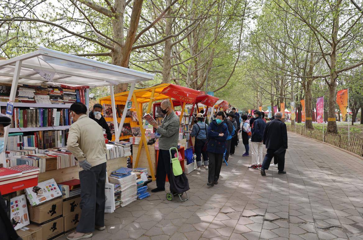 4月14日,读者在2023北京书市朝阳公园主展场阅读选购图书.