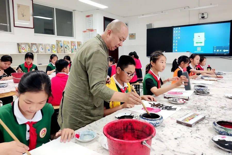 教师张鸿翔走进鲁阳小学,边讲解边示范画萝卜,动作洒脱,笔墨生动有趣