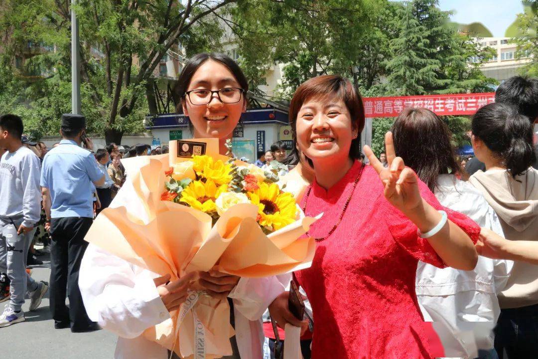 兰州四中考点外,第九中学老师为考生举牌加油.