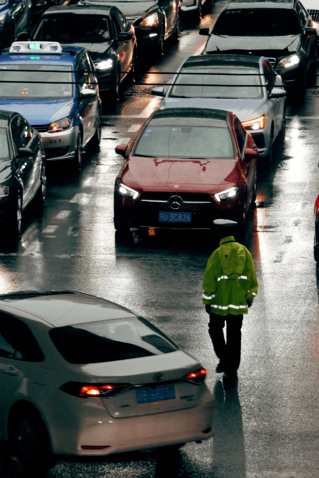 他披着雨衣,在十字路口行色匆匆